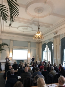 Bild från sal i Börshuset där ett 50 tal deltagare syns bakifrån och Stefan Johansson, Begripsam presenterar längst fram.