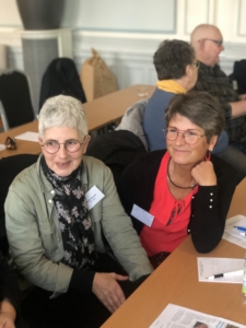 Två kvinnor diskuterar leende med en tredje part som ej syns i bild.