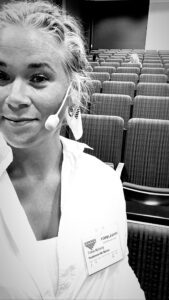 På bilden syns Thilia Nyberg, i svartvitt med headset.