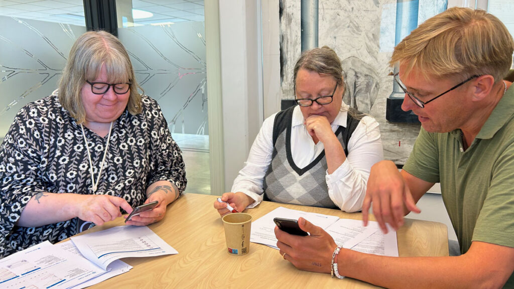 Två deltagare och en läkare testar app tillsammans. Alla ser koncentrerade ut.